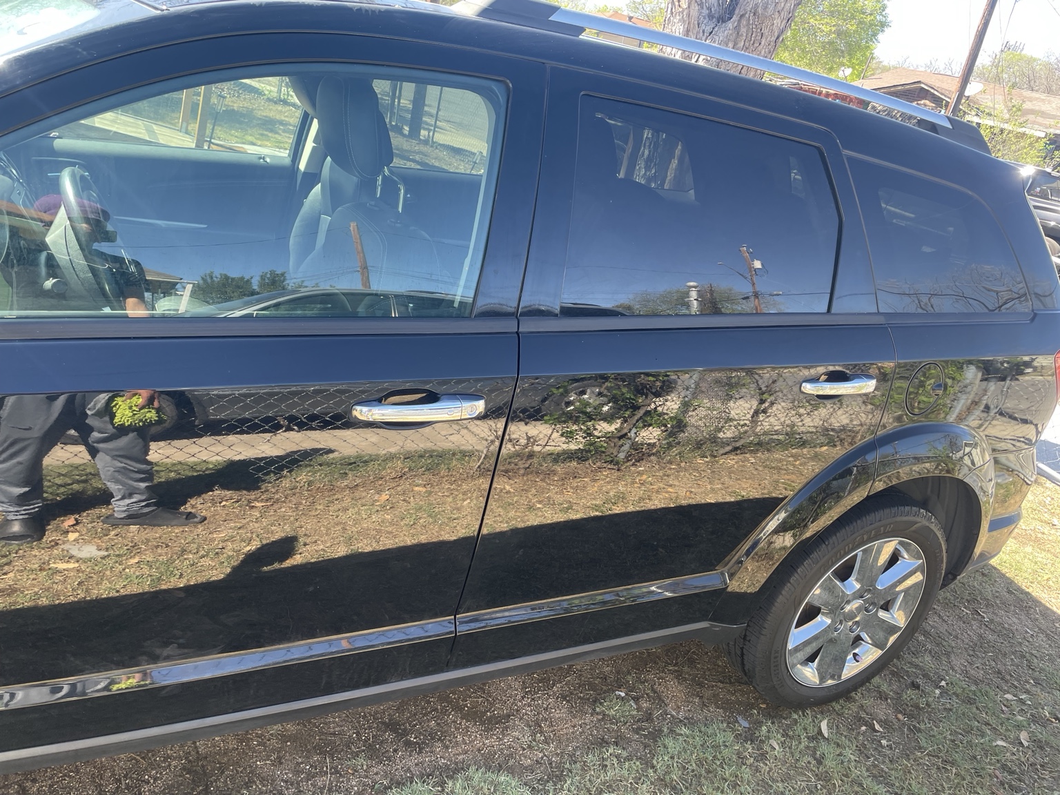 Technician polishing a black Dodge SUV during mobile detail service